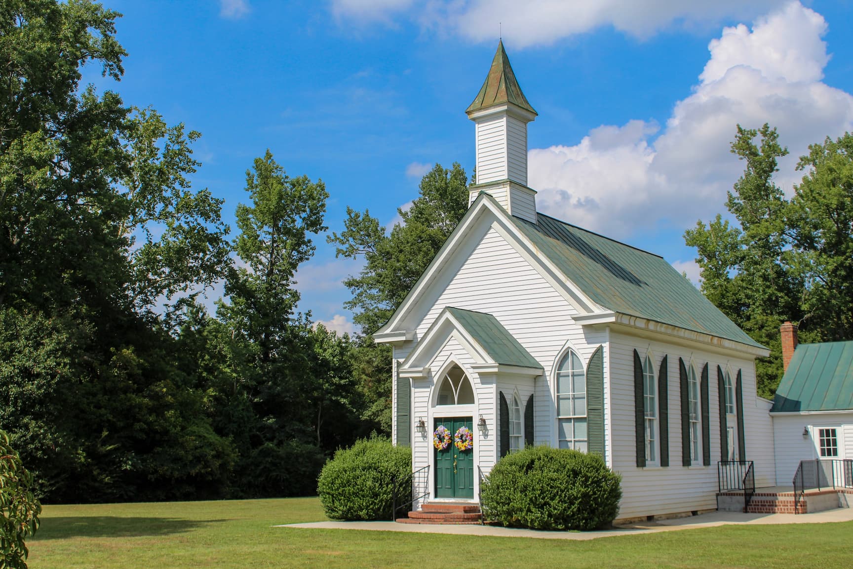 A white country church with a steeple on a sunny day