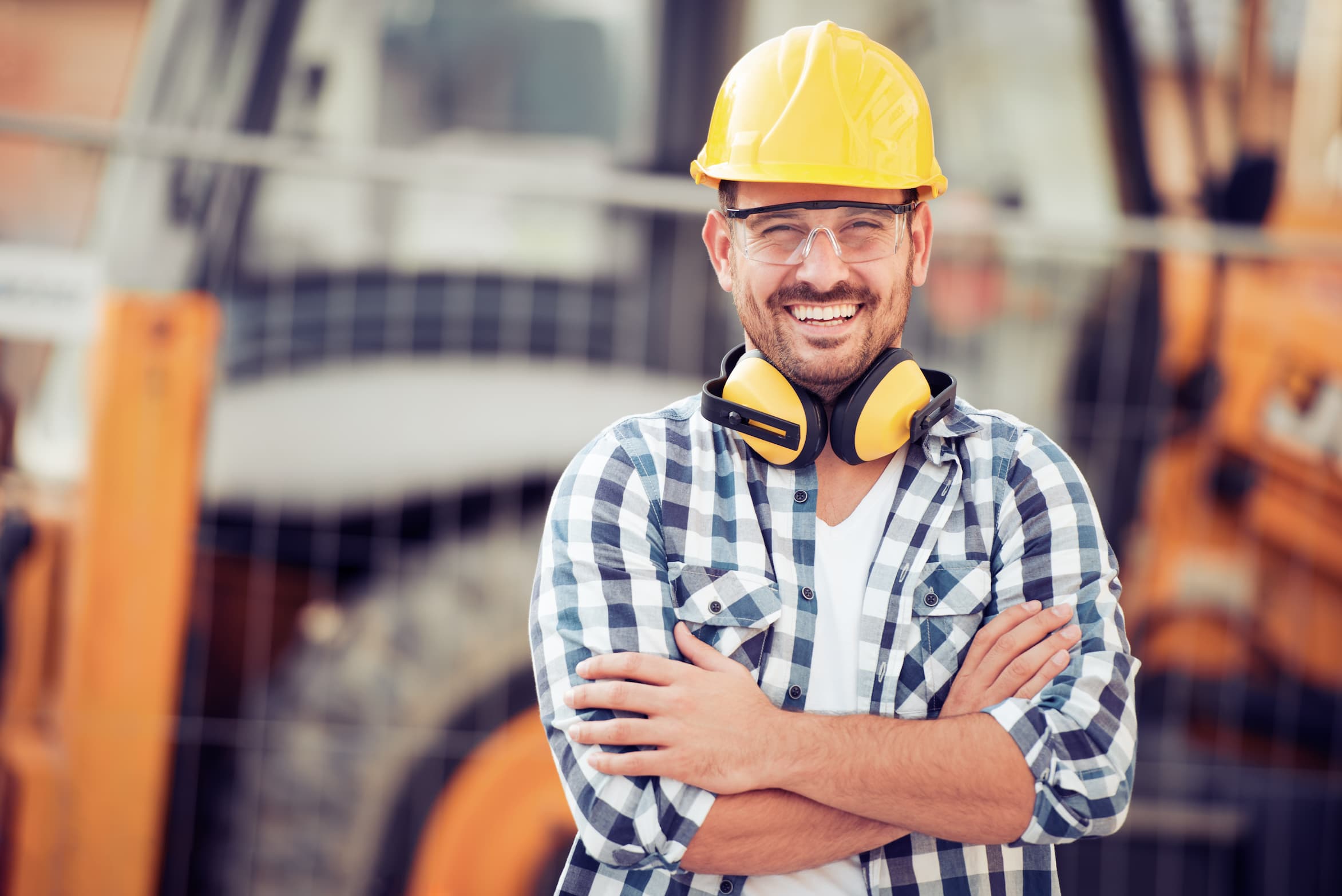 A smiling construction worker in a hard hat on a job site